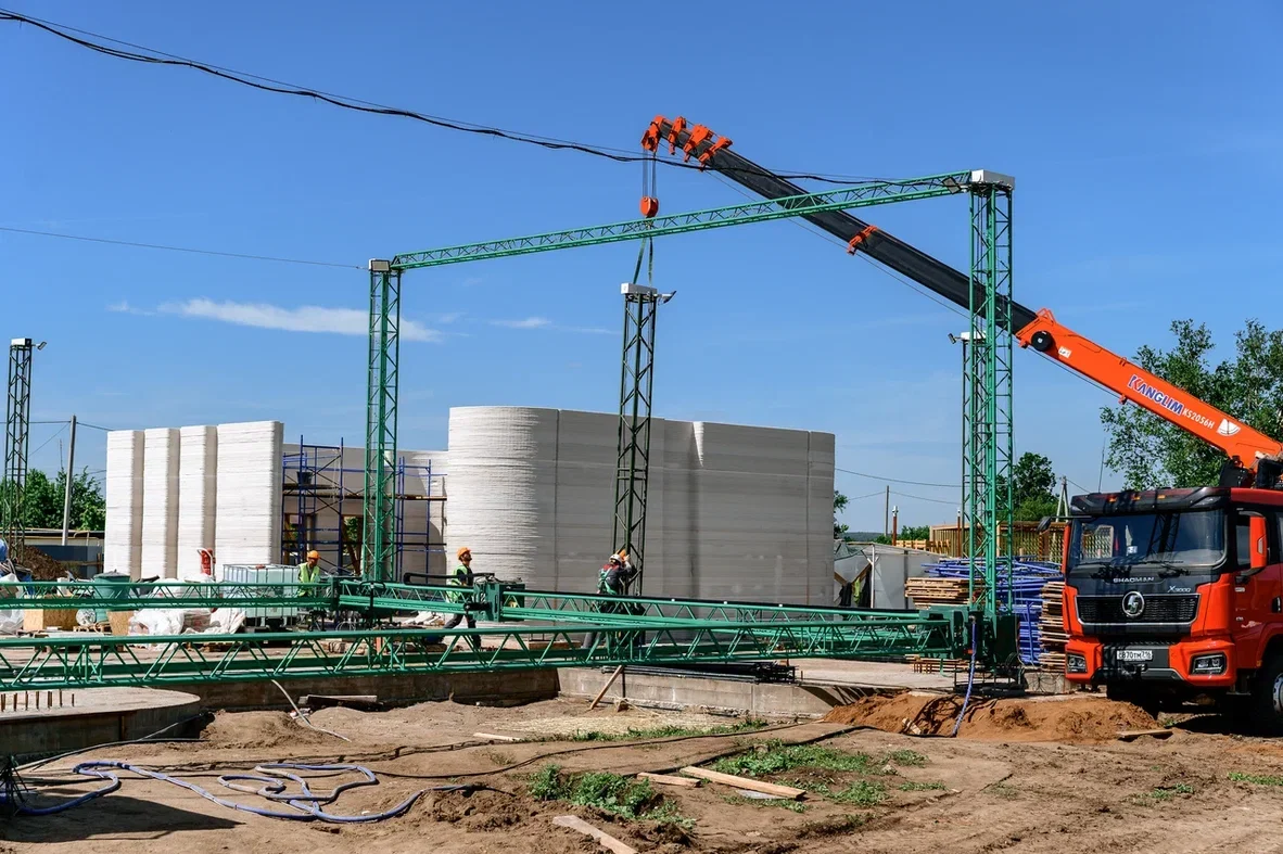 Three synchronized AMTG G2 construction 3D printers producing walls for the Mella shopping center